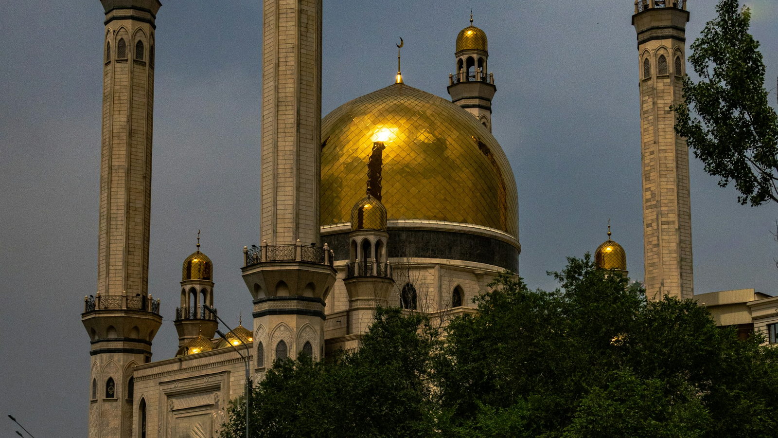 The golden dome and minarets of Almaty Central Mosque at dusk