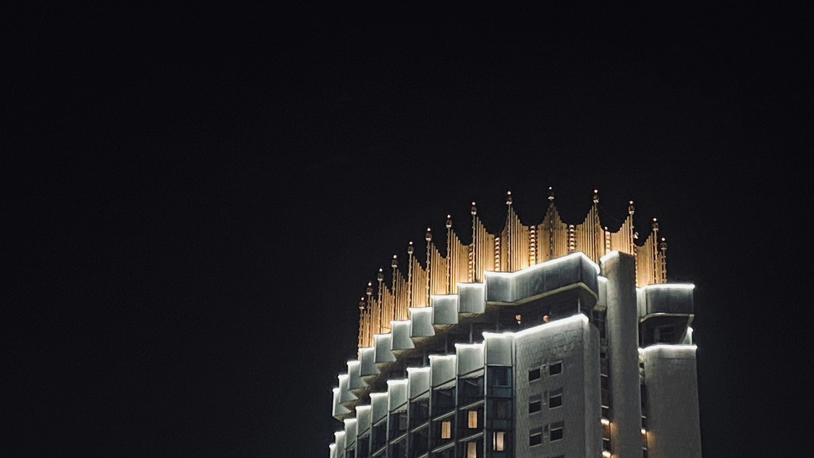 Hotel Kazakhstan&rsquo;s crown-shaped roofline lit gold against the night sky